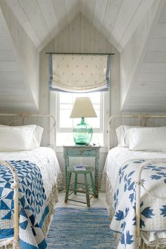 two beds in a room with white walls and blue rugs on the floor next to each other