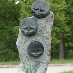 two faces carved into the side of a tree trunk with trees in the back ground