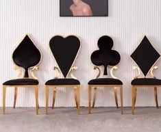 four black chairs with gold frames and hearts on them in front of a white wall