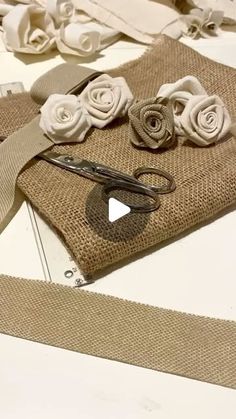 some scissors are laying on burlap with white flowers in the center and one pair of scissors next to it