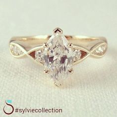 a white diamond ring with two diamonds on the band and an oval shaped center stone