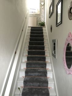 the stairs are lined with black carpet and orange piping to match the wallpaper