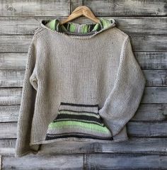 a sweater hanging on a wooden wall with a green and black striped hoodie over it