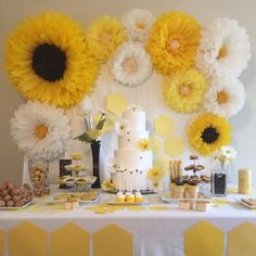 a table topped with yellow and white flowers next to a wall covered in honeycombs