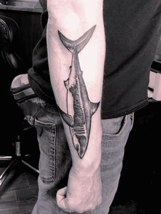 a man with a tattoo on his arm holding a knife in the shape of a fish