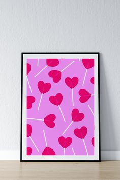 a pink poster with hearts on it sitting on top of a wooden table next to a white wall