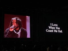 a man that is standing in front of a screen with words on it and a microphone