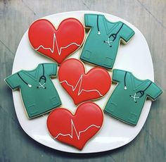 cookies decorated to look like medical scrubs and shirts on a plate with a stethoscope