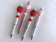 three pens with strawberries on them sitting next to each other