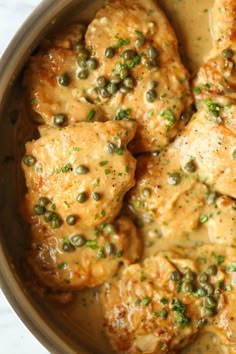 a pot filled with chicken and peas covered in sauce on top of a white counter