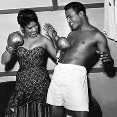 a man and woman standing next to each other with boxing gloves around their necks,