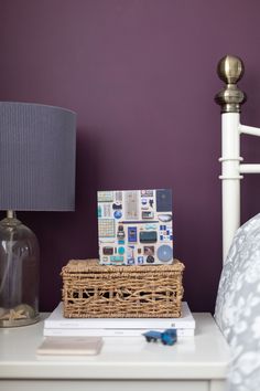 a bed with a basket on top of it next to a night stand and lamp