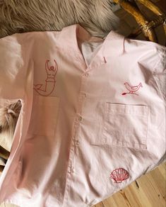 a pink shirt with red designs on it and a cat laying next to the shirt