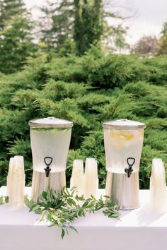 three blenders sitting on top of a white table next to green plants and trees