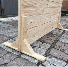 a wooden bed frame sitting on top of a brick floor