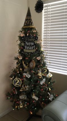 a small christmas tree decorated with new year's eve signs and ornaments in front of a window