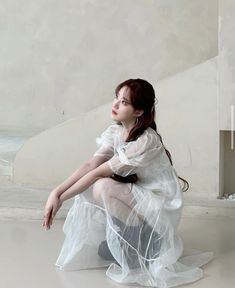 a woman sitting on the ground in a white dress