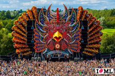 a large colorfully decorated stage at a music festival with lots of people in the foreground