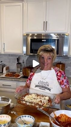 a woman in a kitchen preparing food on a cutting board with bowls and pans