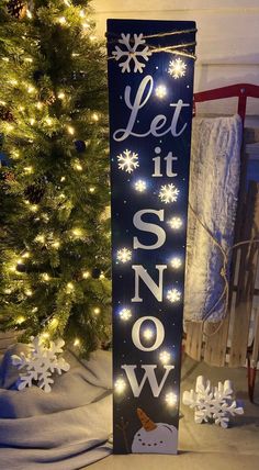 a sign that says let it snow next to a christmas tree