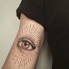 an eye tattoo on the arm with rays coming out of its iris and in front of it