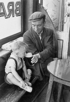 an old man sitting next to a little boy on a bench in front of a window