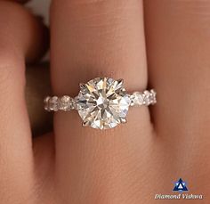 a woman's hand with a diamond engagement ring on her left hand, and the center stone is surrounded by diamonds