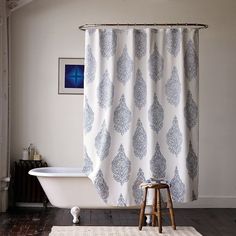 a white bath tub sitting under a window next to a wooden step stool on top of a hard wood floor