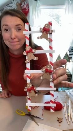 a woman holding up a christmas decoration made out of candy canes and reindeer heads