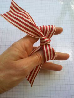 a hand holding a red and white striped bow