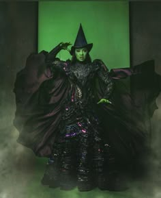 a woman dressed in black and wearing a witch costume with her hands on her hips