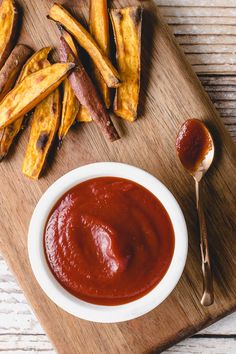 homemade low carb ketchup in a bowl next to french fries on a cutting board