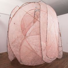 a large pink object sitting on top of a wooden floor next to a white wall