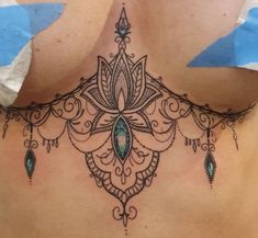 a woman's back with an intricate tattoo design on her neck and lower back