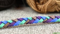 a multicolored braid on the floor next to a ball of yarn