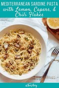 a bowl of pasta with lemon, capers and chili flakes on a white table