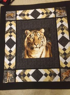 a tiger is shown in the center of a quilted wall hanging on a table