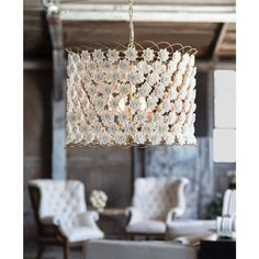 a chandelier hanging from the ceiling in a living room with chairs and tables