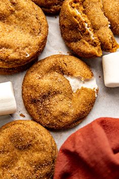 several cookies and marshmallows are on a piece of parchment paper next to a red napkin