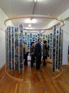 a group of people standing around in a room with pictures on the walls and wood floors