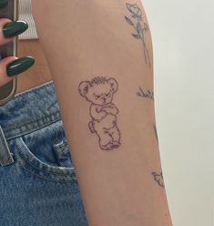 a woman's arm with a small tattoo of a teddy bear