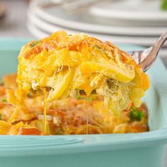 a piece of food is being lifted from a blue casserole dish with broccoli and cheese