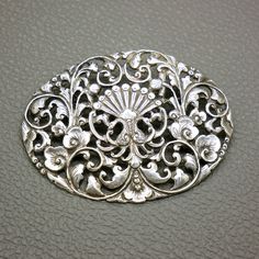 This stunning large antique oval brooch, crafted from 800 silver, features exquisite paradise birds and flower decor. This piece, originating from the 1930s, showcases the intricate artistry of Javanese Yogya Yogyakarta jewelry with its detailed repousse technique, making it a timeless treasure. The central part of this oval openwork pin is decorated with an intricately detailed flower ornament and two paradise birds, which traditionally symbolize happiness in love and long-lasting relationship. Ornate Oval Filigree Brooches, Victorian Oval Filigree Brooches, Ornate Oval Brooches For Anniversary, Ornate Oval Anniversary Brooches, Antique Oval Engraved Brooches, Oval Engraved Brooches For Anniversary, Ornate Oval Engraved Brooches, Art Nouveau Wedding Brooches With Filigree, Art Deco Oval Brooch For Anniversary