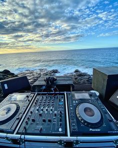 dj equipment sitting on top of a wooden table next to the ocean