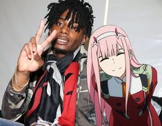 a man with dreadlocks sitting next to a cardboard cutout of an anime character