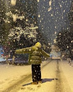 a person is standing in the snow with their arms spread out and looking at something