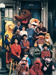 a group of people posing for a photo with sesame street characters