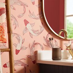 a bathroom with pink wallpaper and gold mirror above the sink is decorated with koi fish