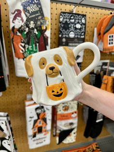 a person holding up a coffee mug with a dog on it in front of halloween decorations