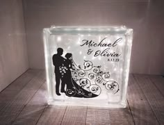 a lighted glass block with a silhouette of a bride and groom holding each other's hand